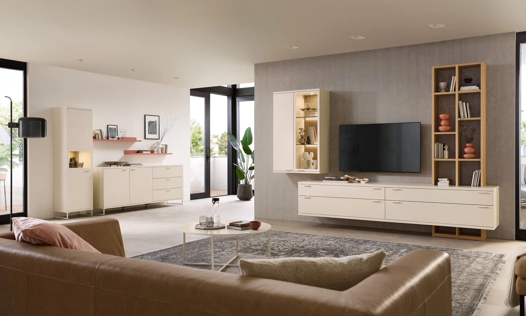 Man sieht ein Wohnsystem aus hellen Möbeln mit einem Holzregal und Beleuchteten Vitrinen.